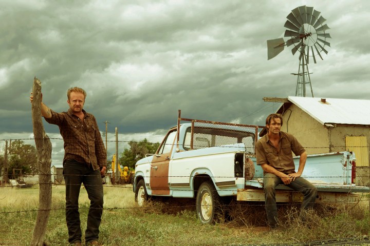 Ben Foster stands near Chris Pine in Hell or High Water.