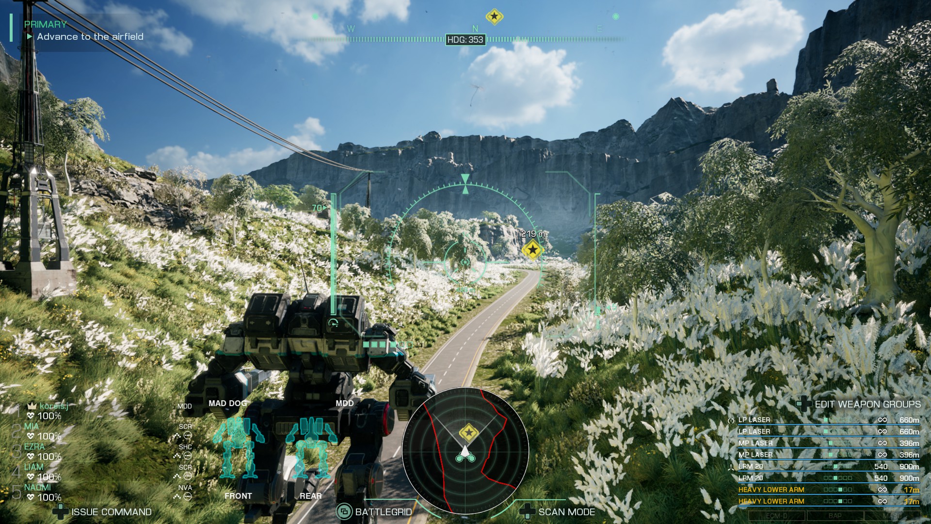 A medium sized mech travels along the road under blue skies surrounded by flowers in Mechwarrior 5 Clans.